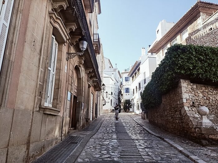 Calle empedrada del casco antiguo de Sitges, con fachadas señoriales y casas blancas