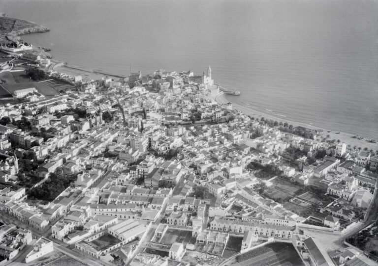 Vista aérea histórica de Sitges hacia 1930, con el promontorio de la Punta, la iglesia y el casco antiguo junto al mar