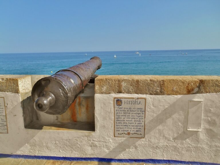 Tramo de la muralla de Sitges junto al mar con un cañón antiguo en el Baluard